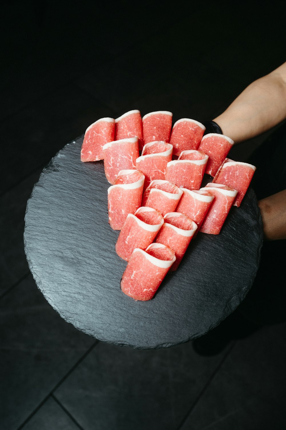 a person holding a plate of watermelon slices