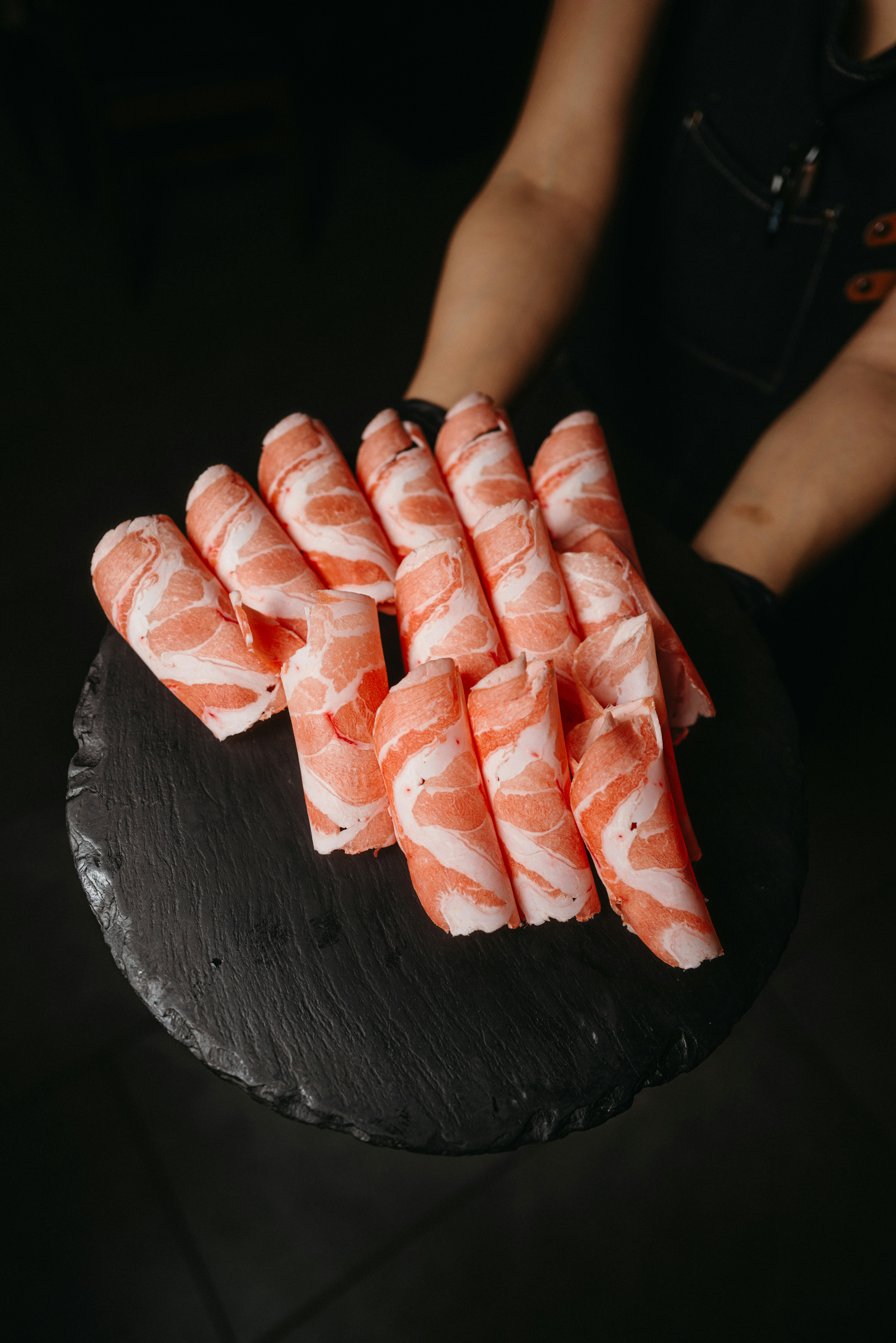 a person holding a plate of sushi on a table
