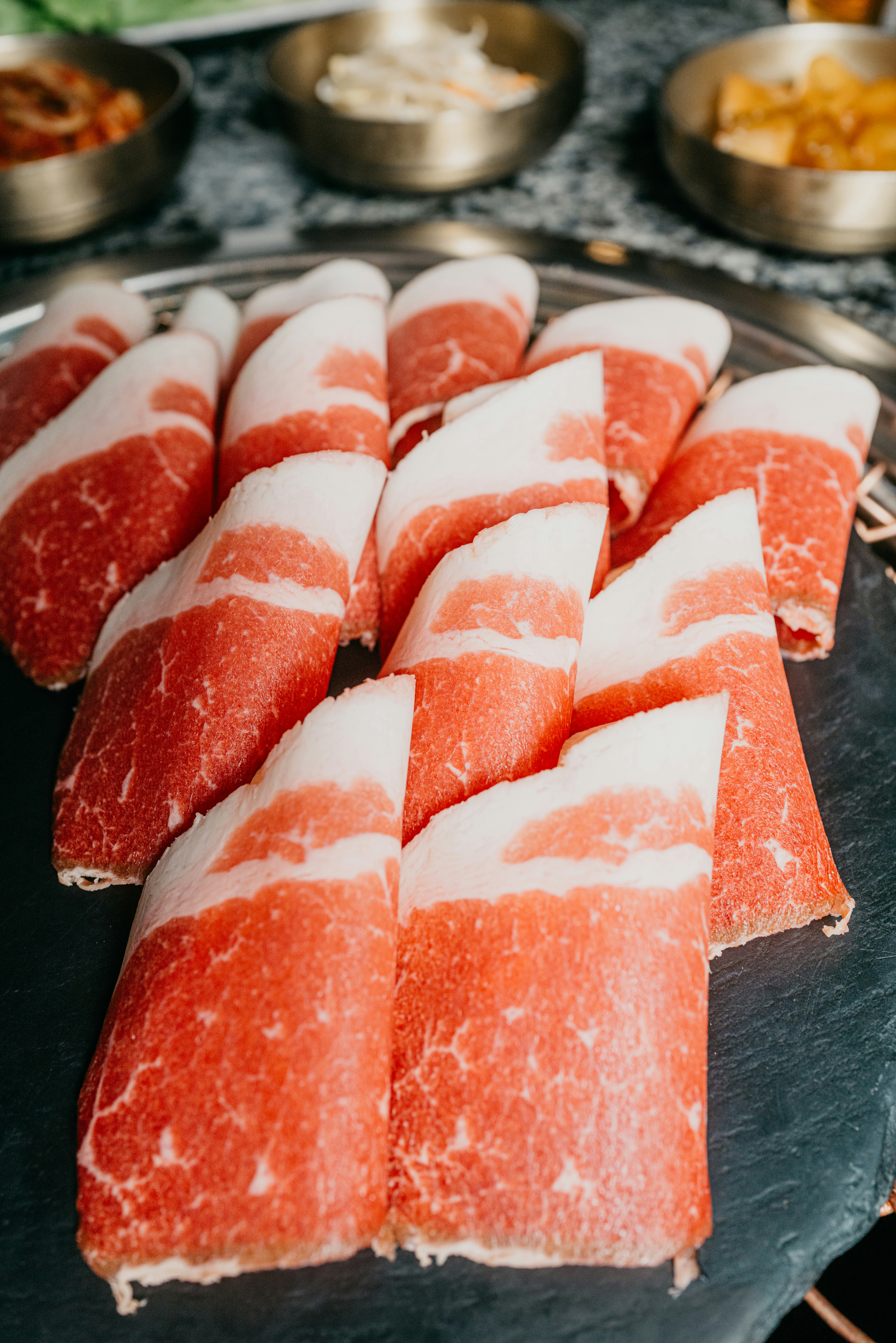 Sliced beef sirloin joint on dark slate platter, glistening surface, smoke ring visible