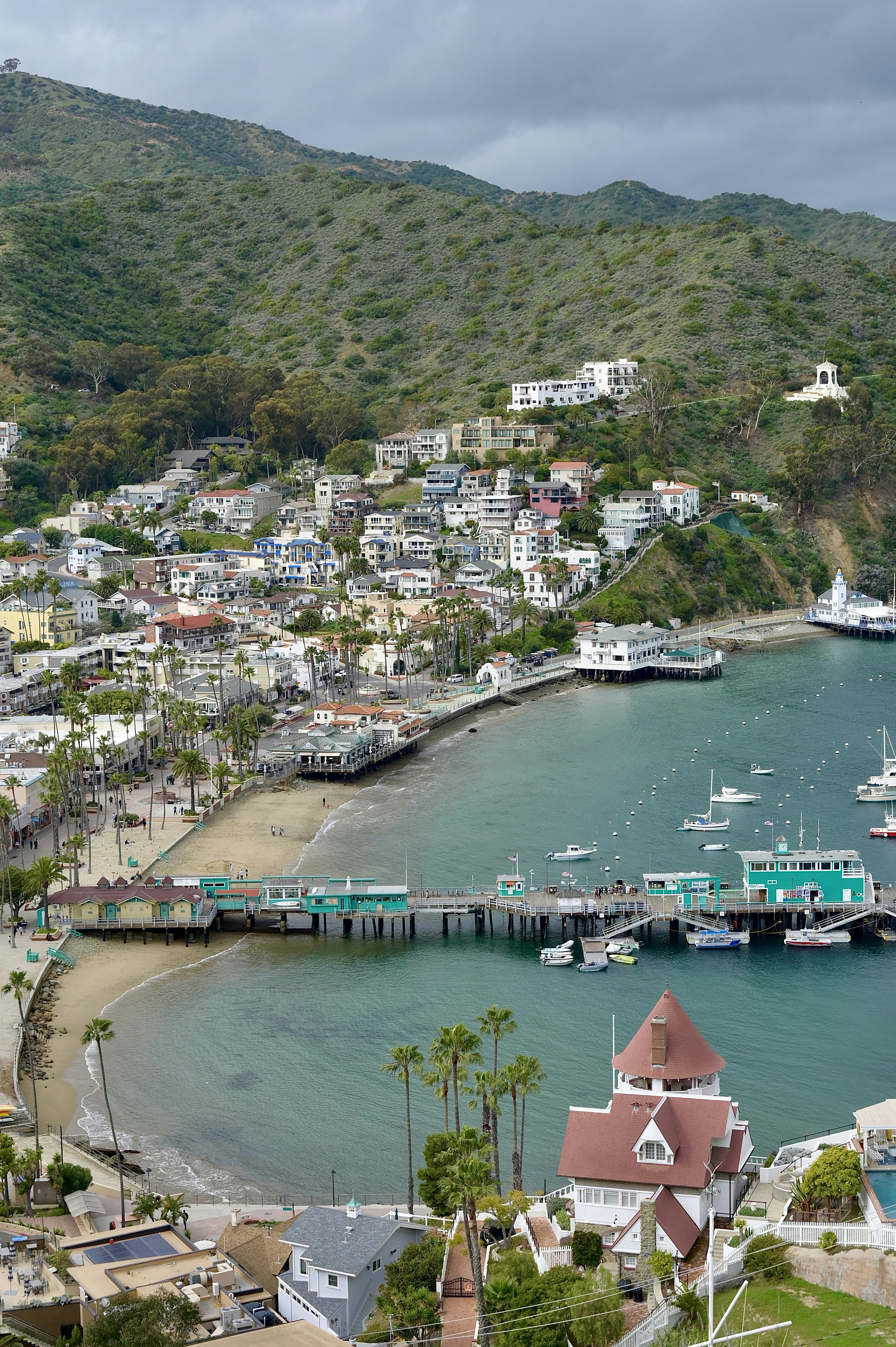 a harbor filled with lots of boats next to a lush green hillside