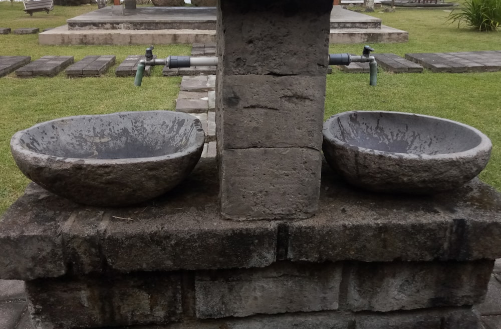 a couple of stone bowls sitting on top of a stone wall