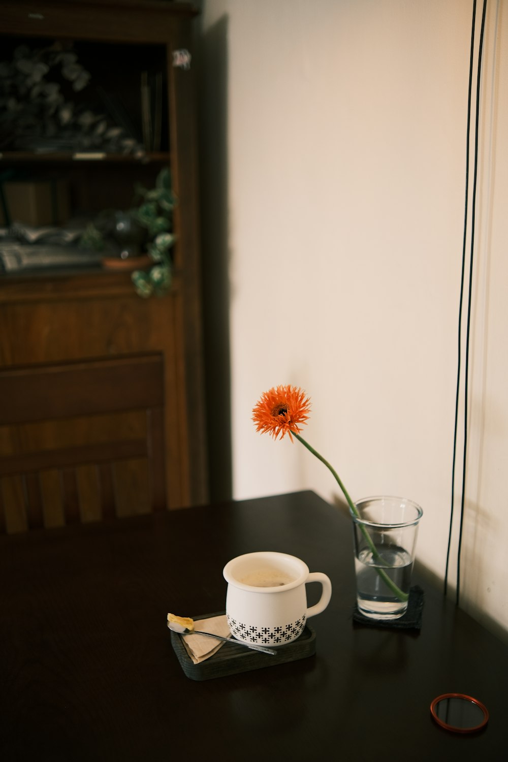 une table avec une fleur et une tasse dessus