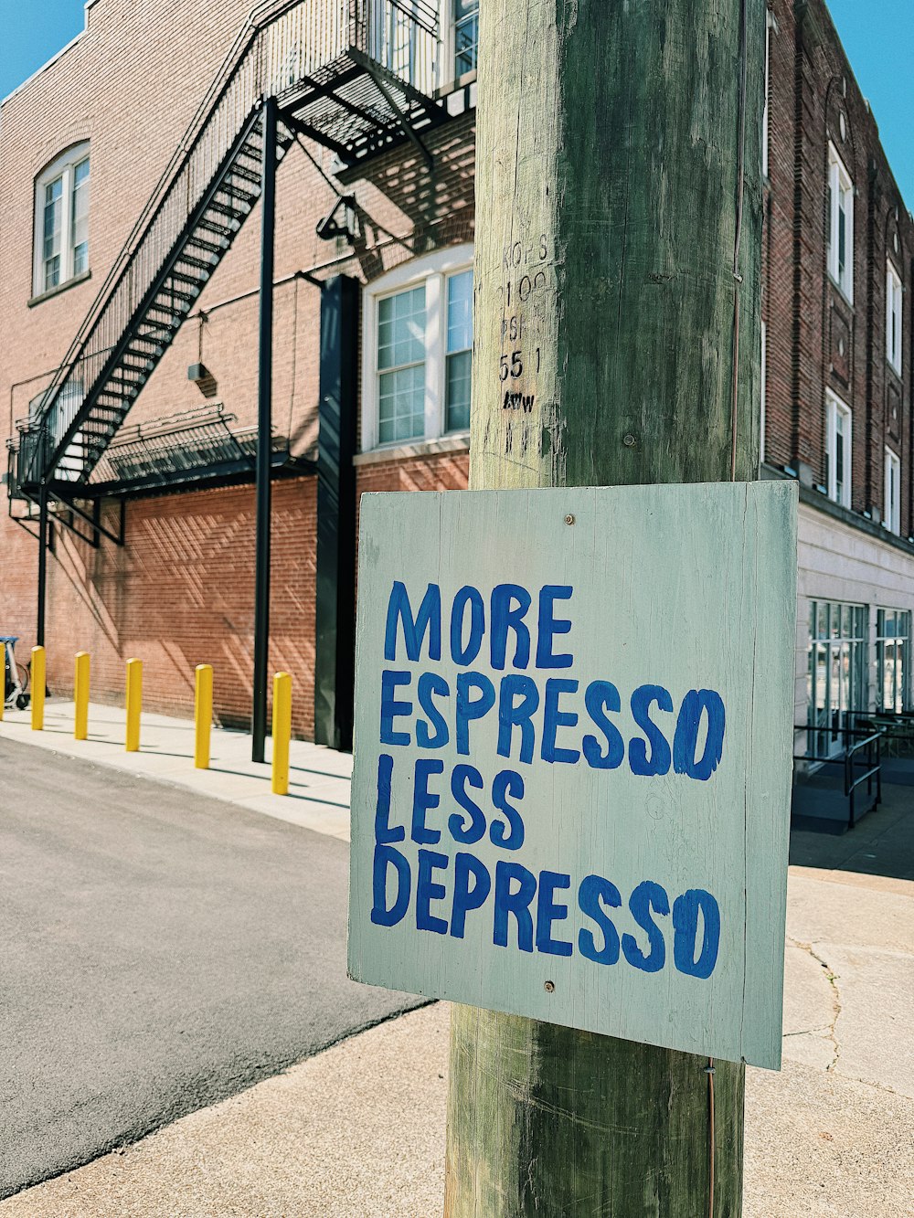 a sign on a telephone pole that says more espresso less depresso