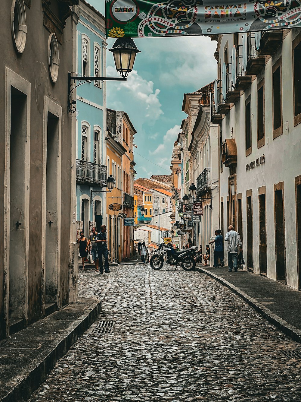 uma rua de paralelepípedos com uma motocicleta estacionada na lateral