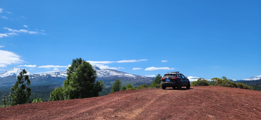 a truck driving down a dirt road with mountains in the background