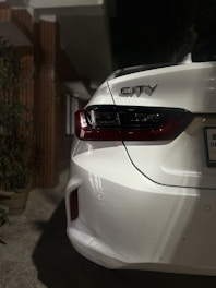 the back end of a white car parked in a driveway
