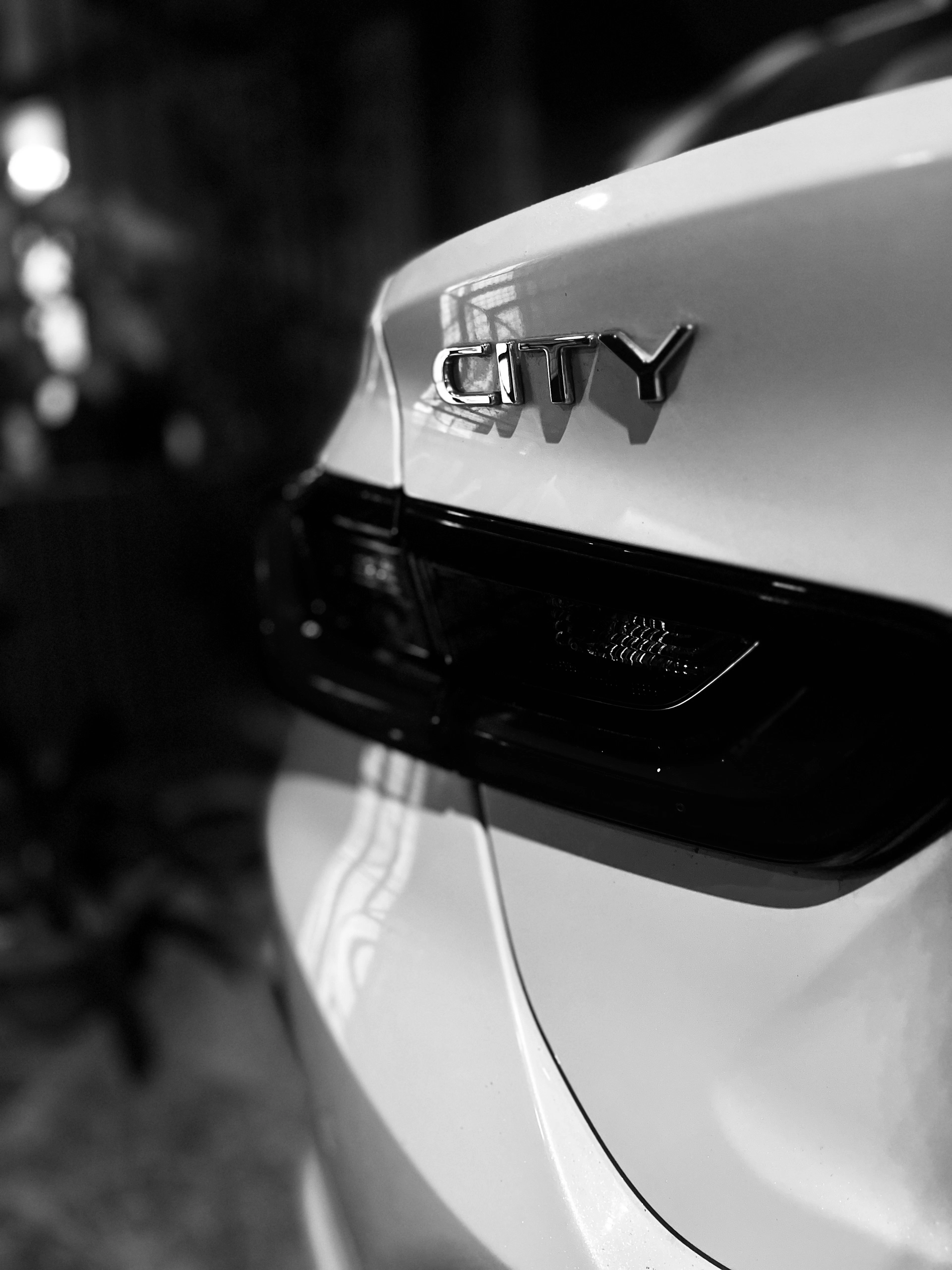 White Honda City, rear three-quarter view at night