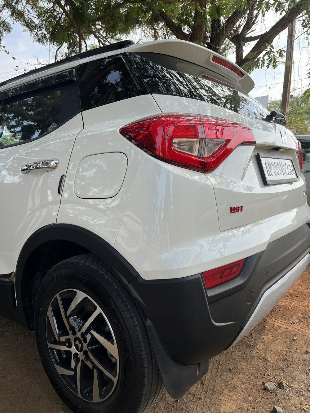 the rear end of a white suv parked on a dirt road