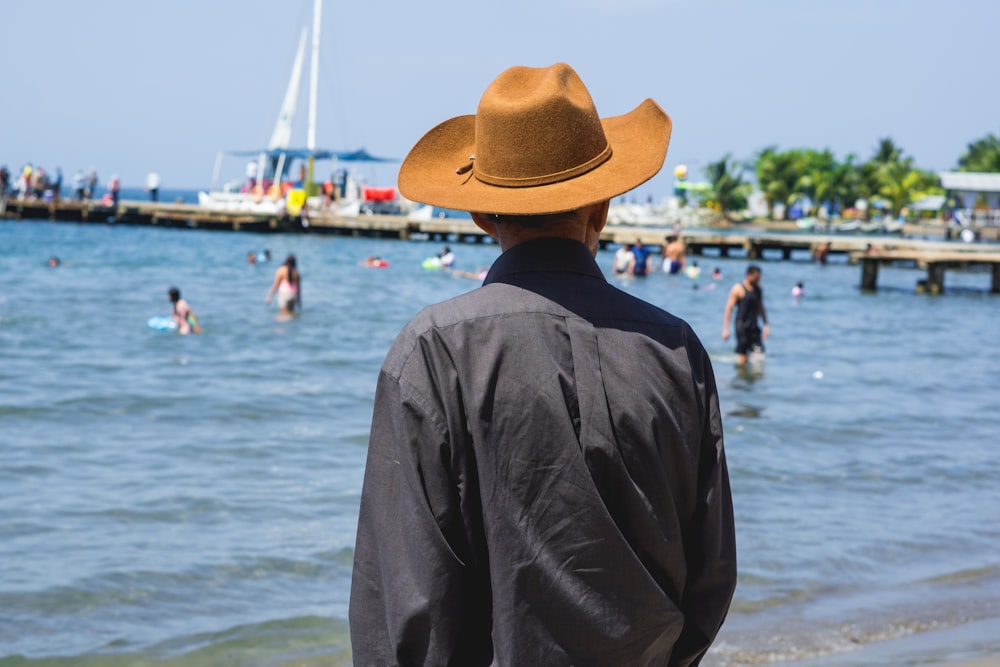 a man wearing a hat standing on a beach