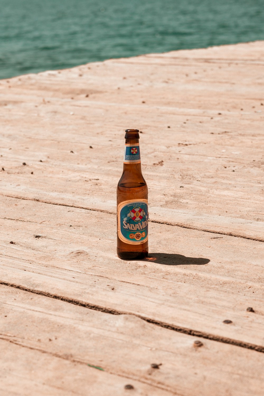 a bottle of beer sitting on top of a wooden dock