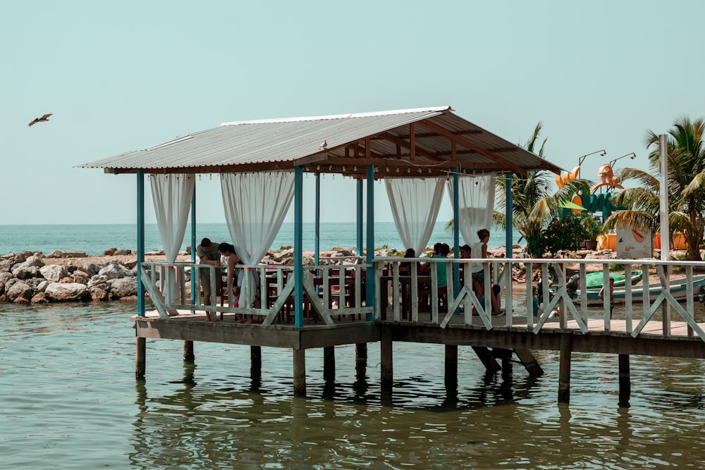 a gazebo sitting on top of a pier next to the ocean