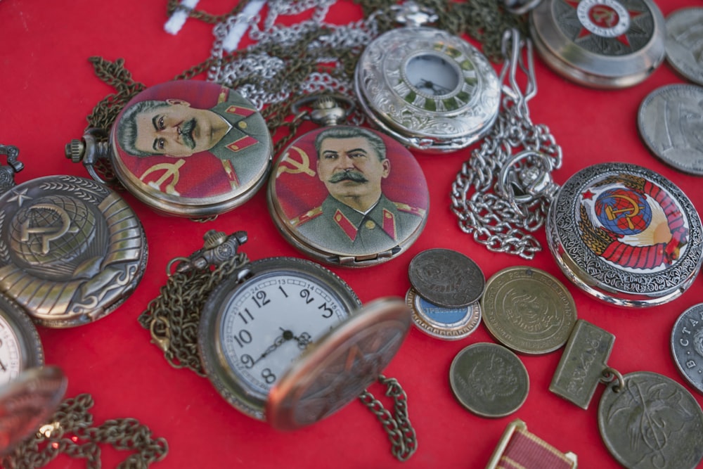 a red table topped with lots of different types of pocket watches