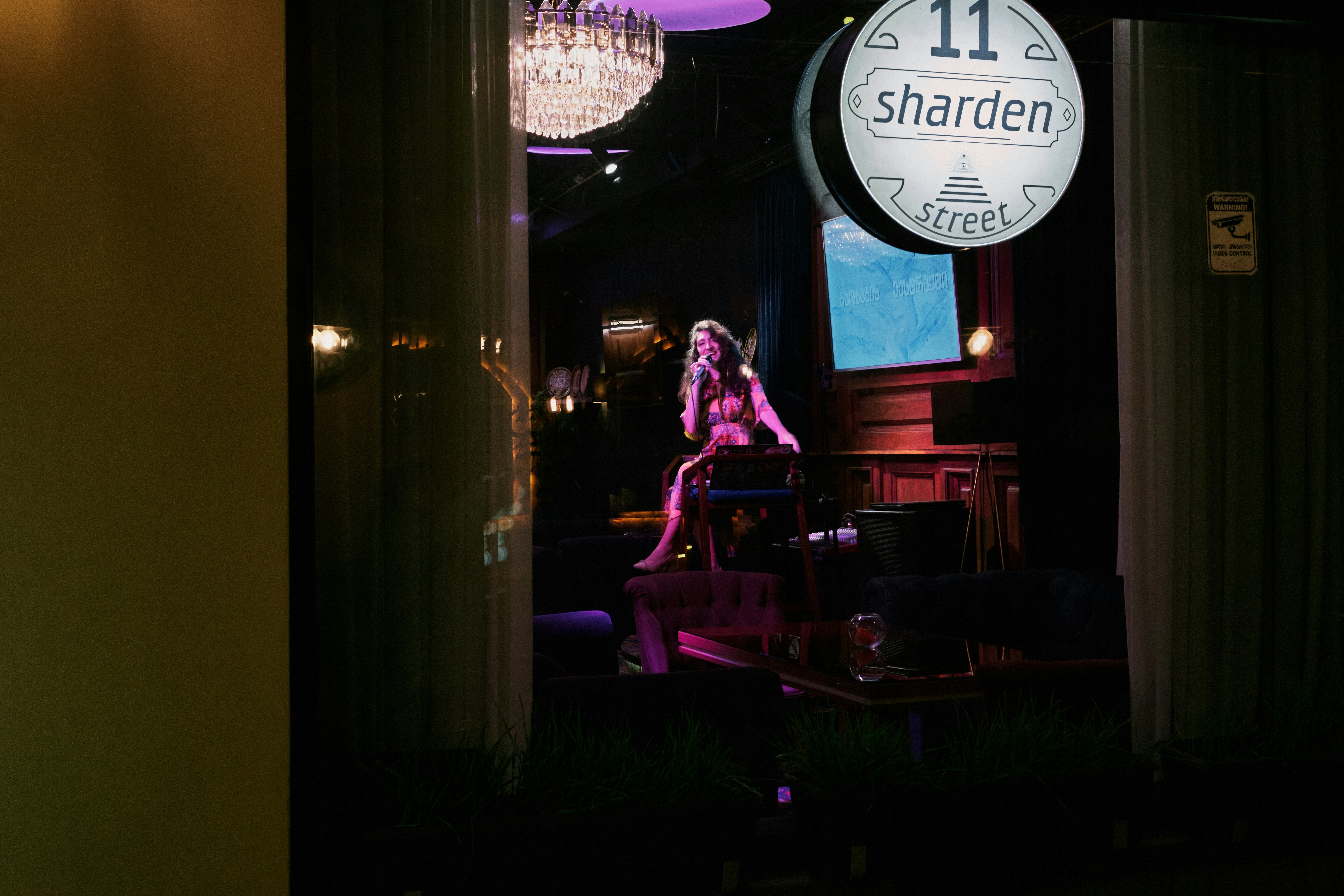 Artista femenina en el escenario con micrófono, iluminación vibrante púrpura y magenta