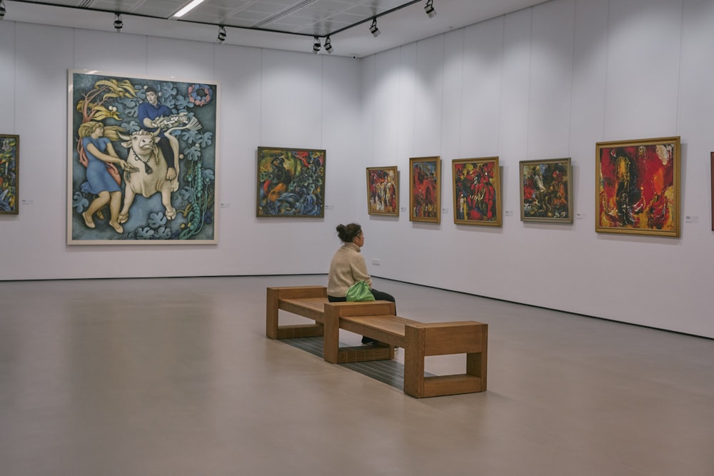 a woman sitting on a bench in a museum