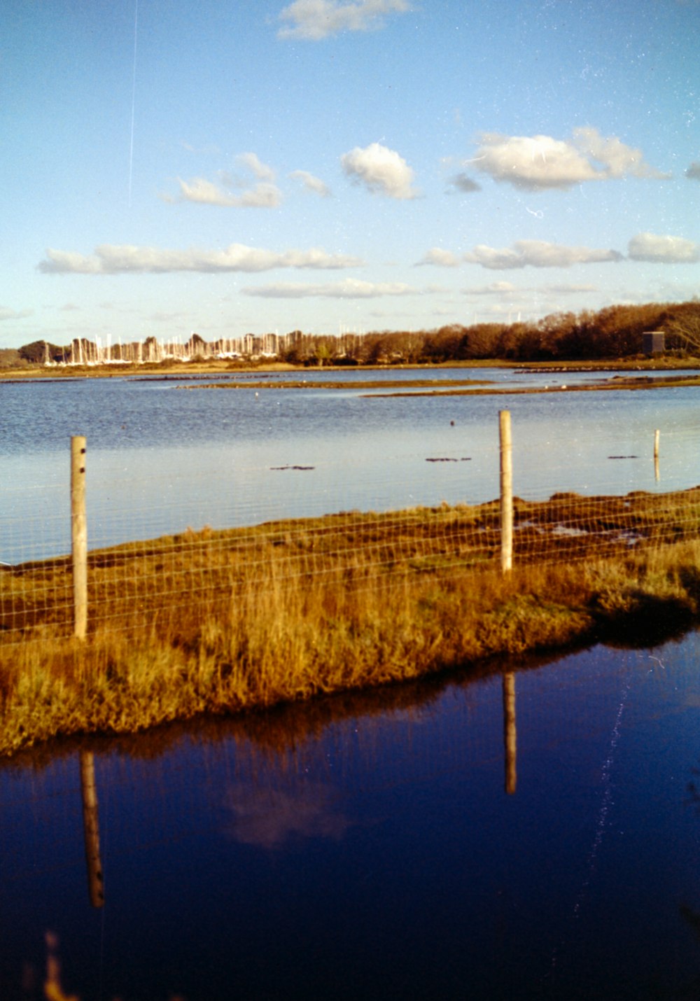 a body of water with a fence in the foreground