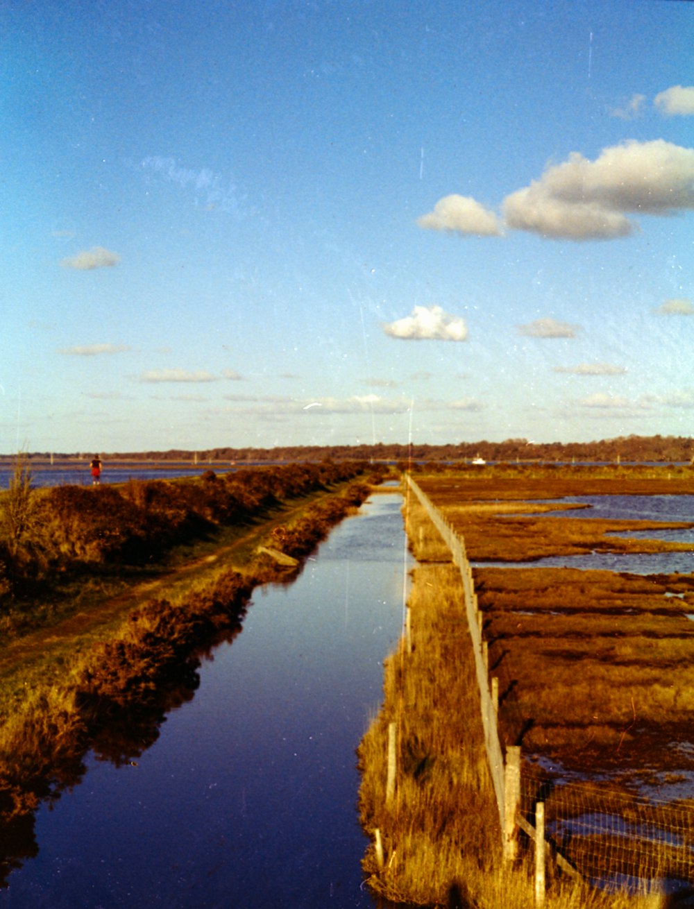 a long stretch of water next to a fence