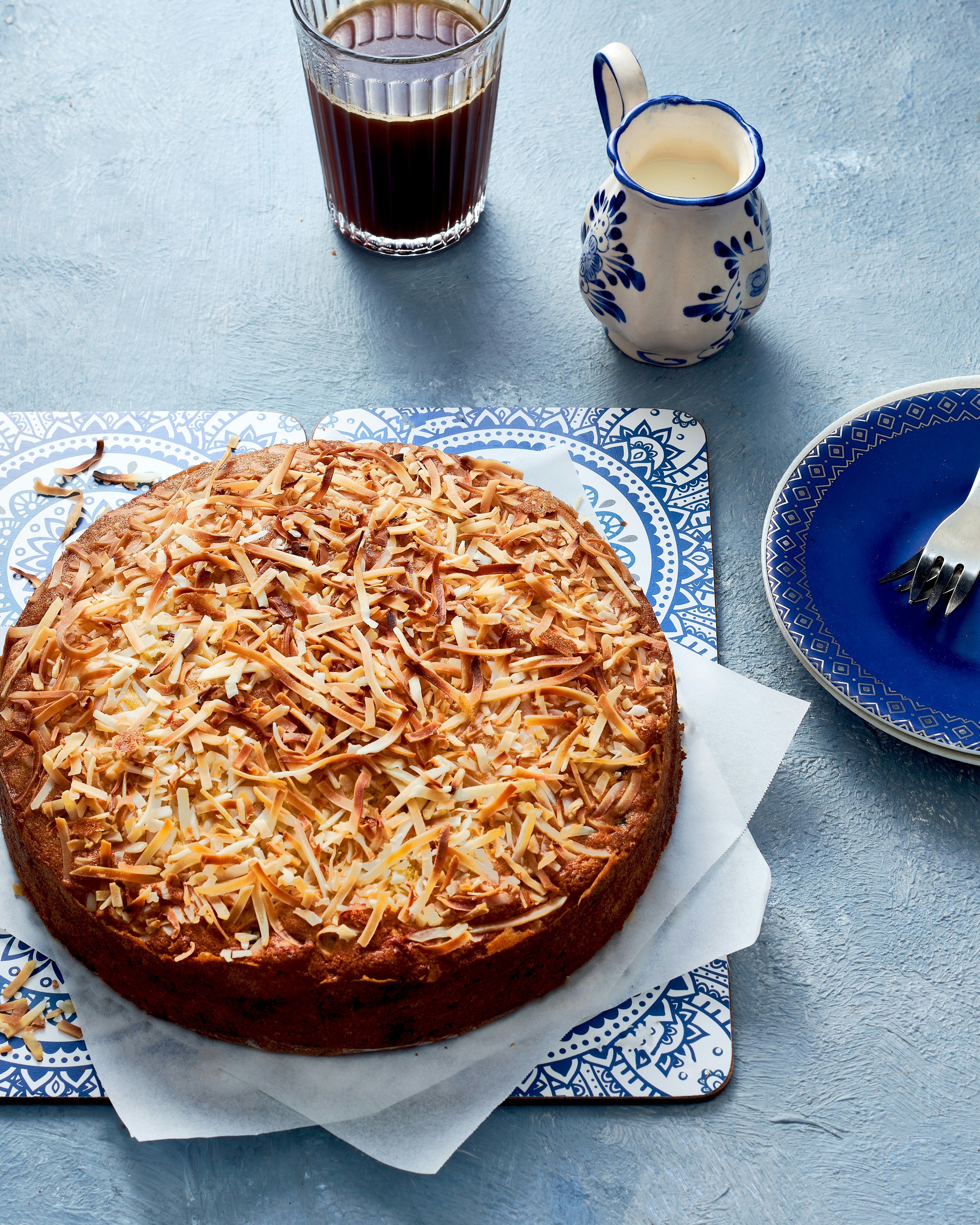 a cake on a blue and white plate next to a cup of coffee