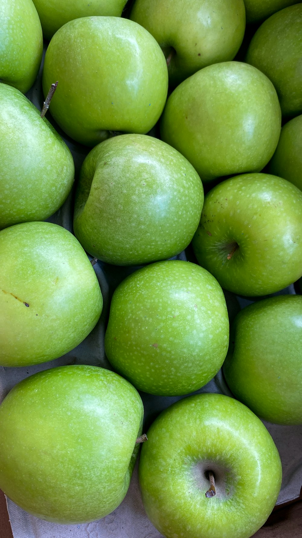 a pile of green apples sitting on top of a table