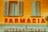 a yellow building with shutters and a sign that says farmacia