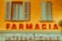 a yellow building with shutters and a sign that says farmacia