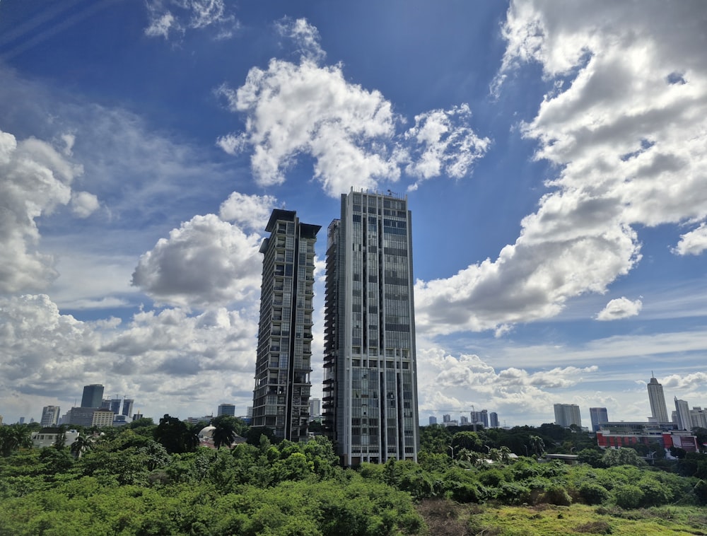 a couple of tall buildings sitting in the middle of a lush green field