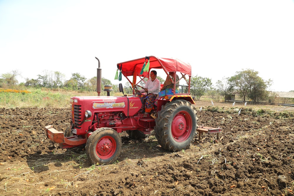 a man driving a red tractor in a field