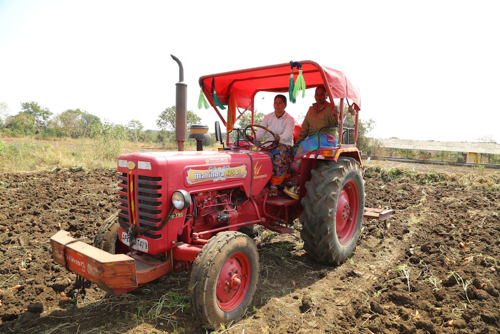 a man driving a red tractor through a field