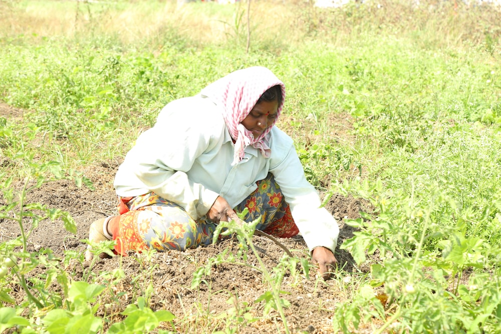 a woman kneeling down in the middle of a field