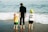 a man and two children are standing on the beach