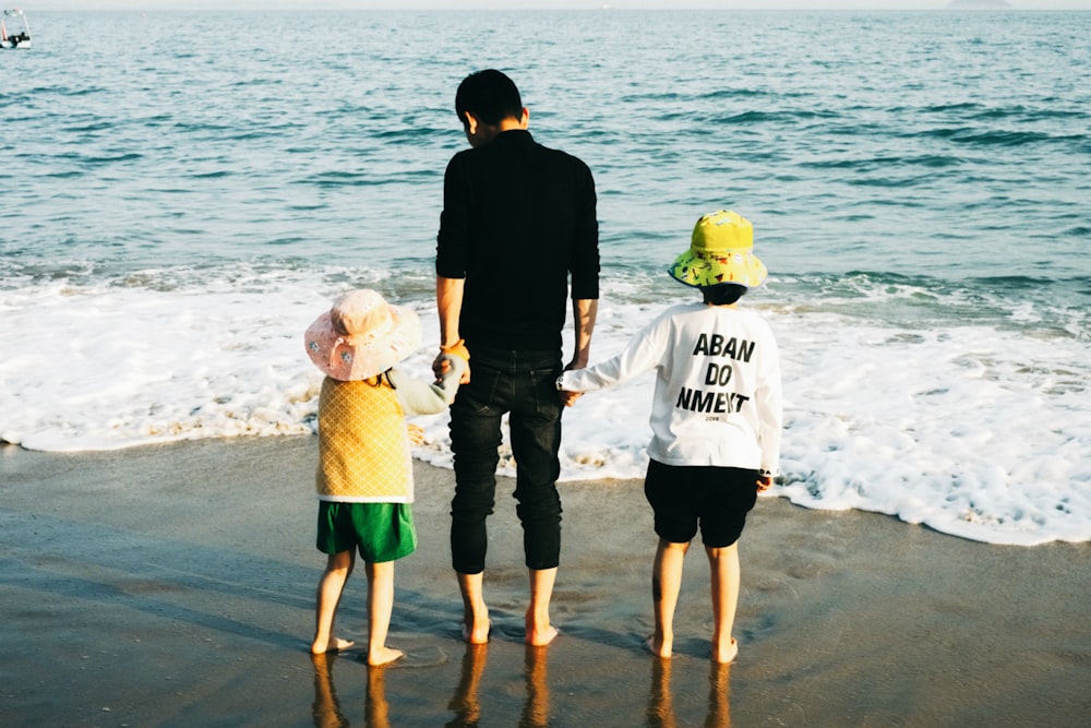 a man and two children are standing on the beach