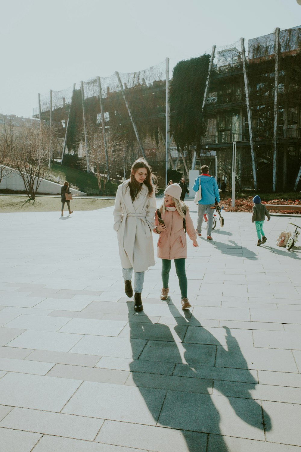 a woman and a little girl walking down a sidewalk