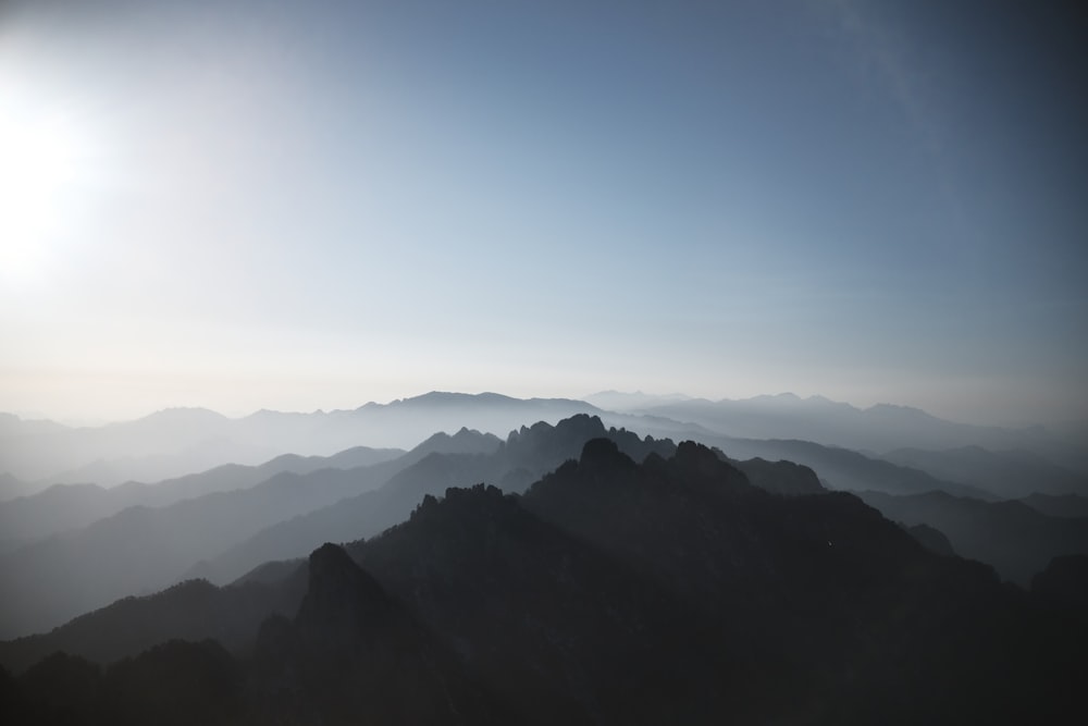 a view of a mountain range with the sun in the background