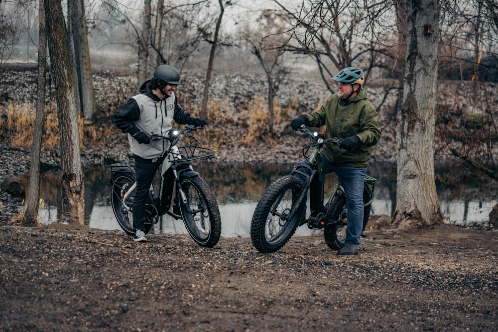 a couple of men standing next to each other on dirt bikes