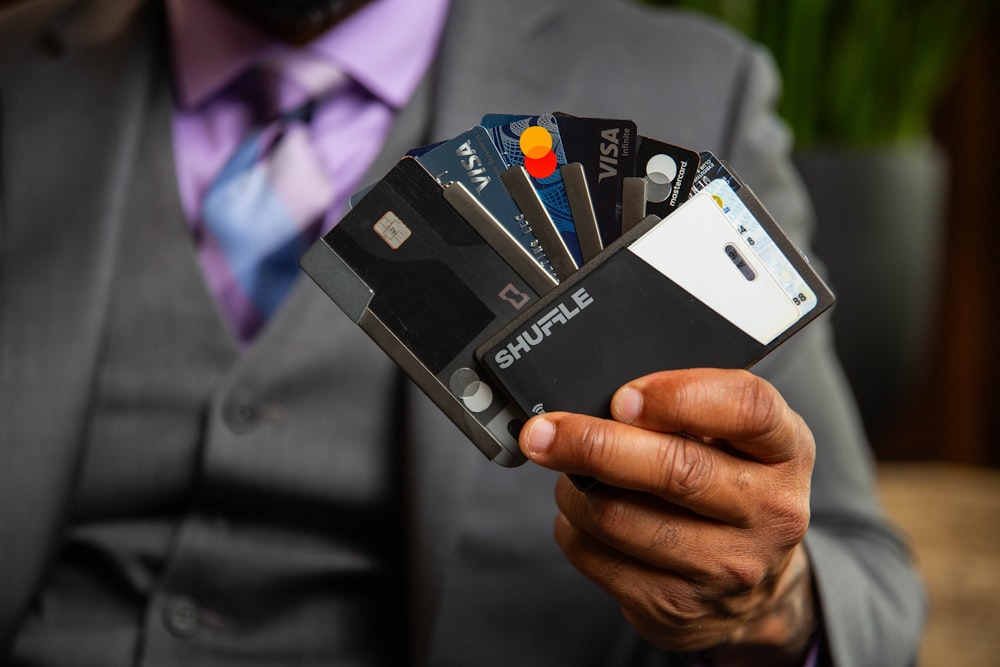 un uomo in giacca e cravatta con in mano quattro carte di credito