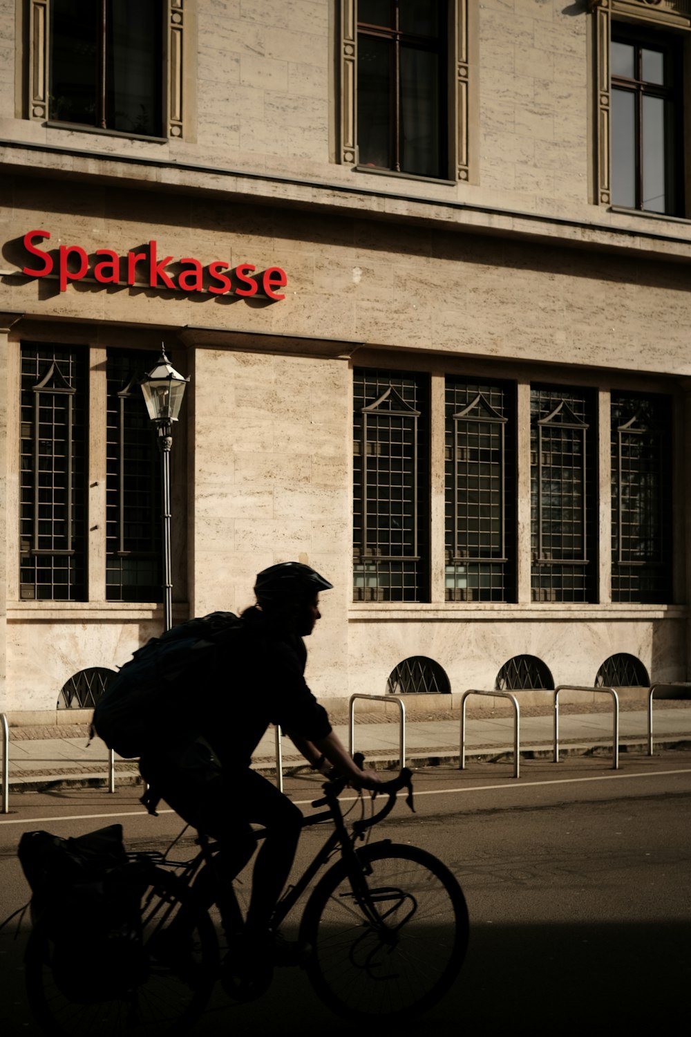 a man riding a bike down a street next to a tall building