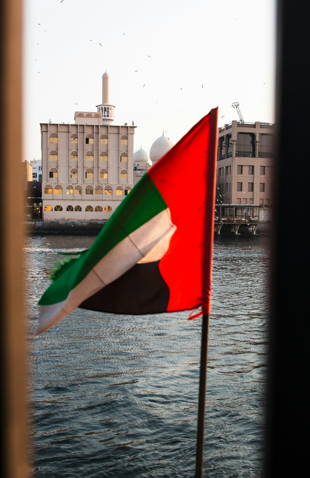 a flag flying in front of a body of water