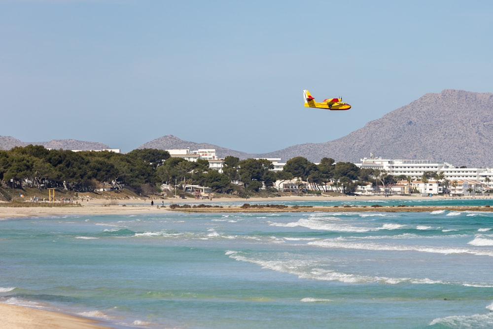 a plane flying over the ocean with a city in the background