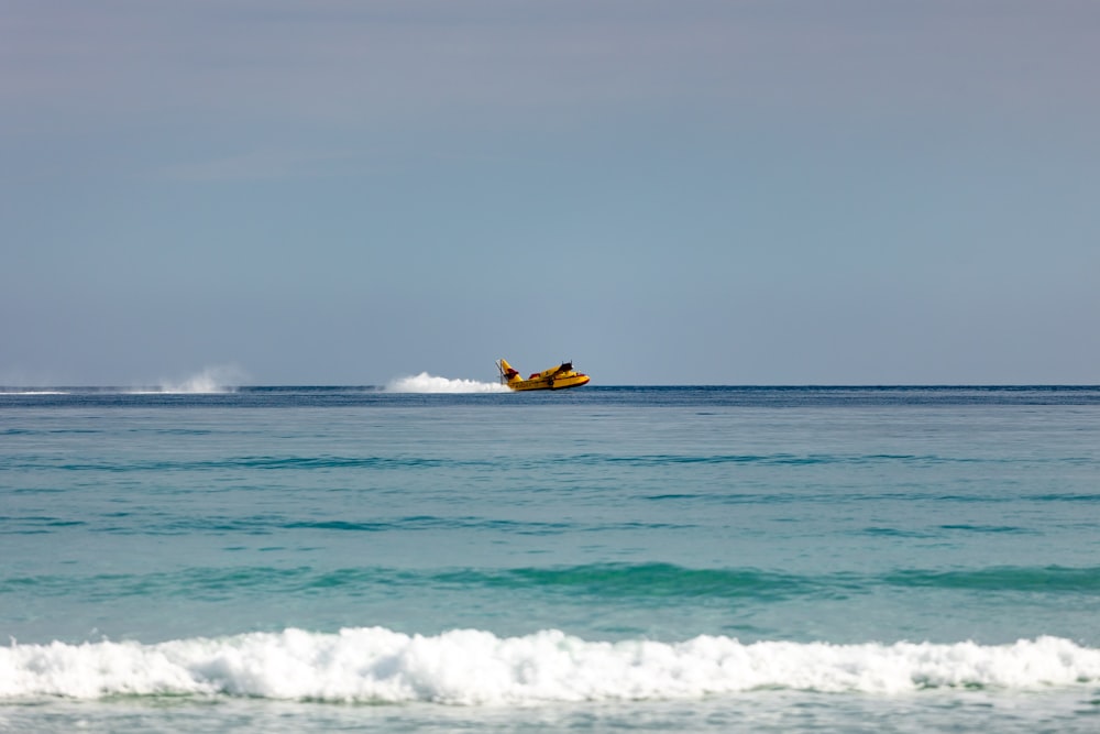 a plane flying over the ocean with a wave coming in