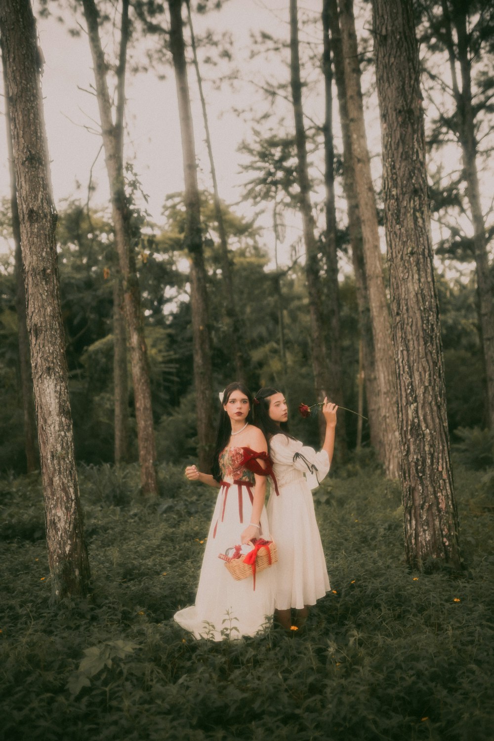 a couple of women standing next to each other in a forest