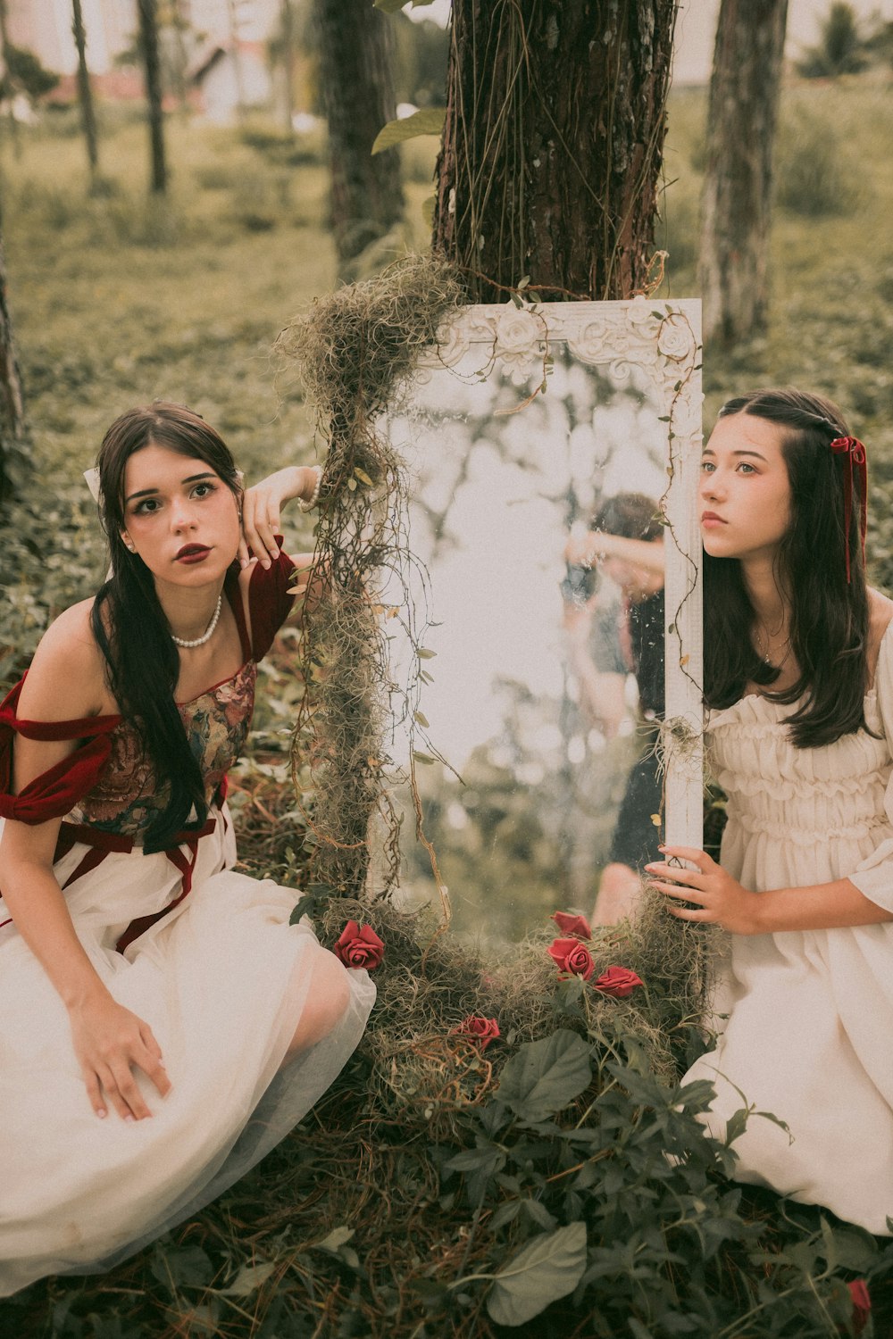 two women dressed in white sit in front of a mirror