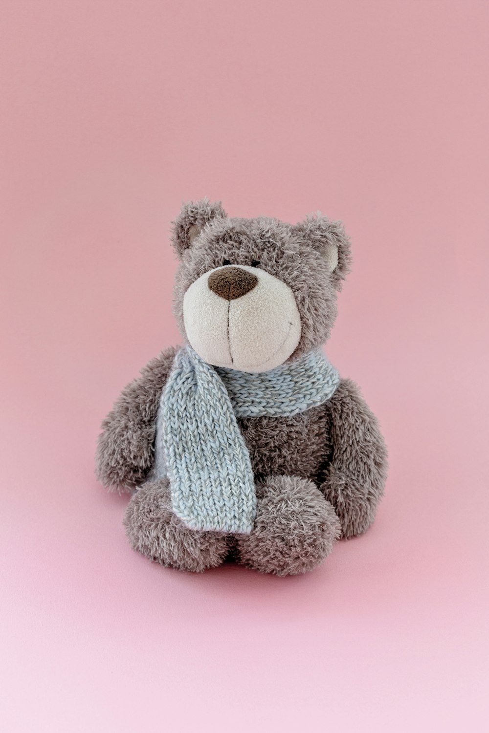 a gray teddy bear with a scarf around its neck
