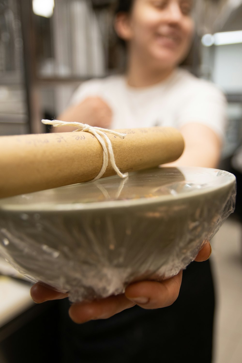 a woman is holding a bowl with a rolling pin in it