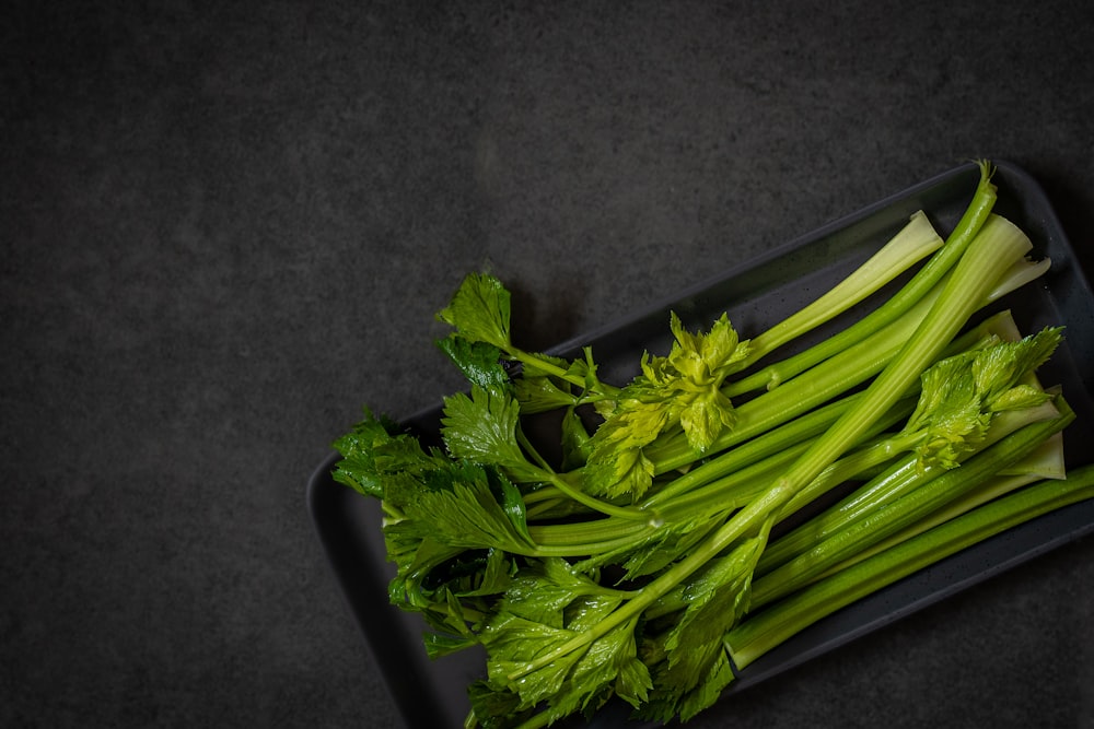 a bunch of celery sitting on top of a black tray
