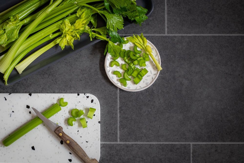 a cutting board topped with celery next to a knife