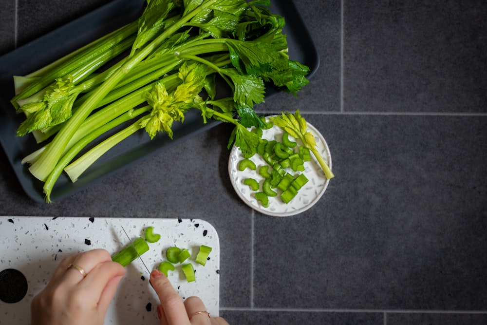a person chopping celery on a cutting board