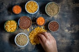 a person touching a bowl of lentils on a table