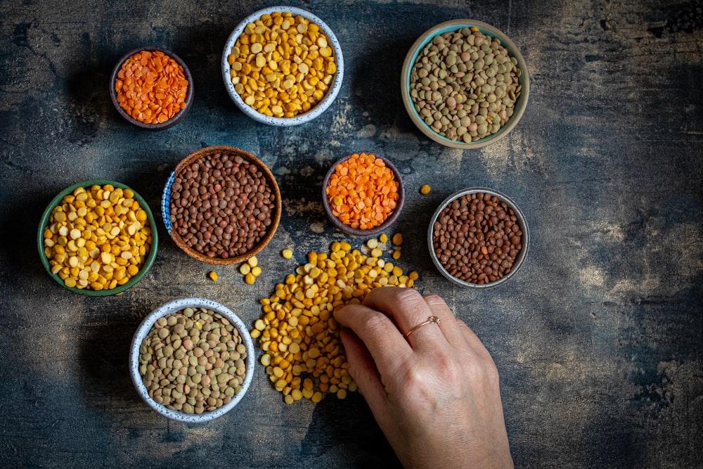 a person touching a bowl of lentils on a table