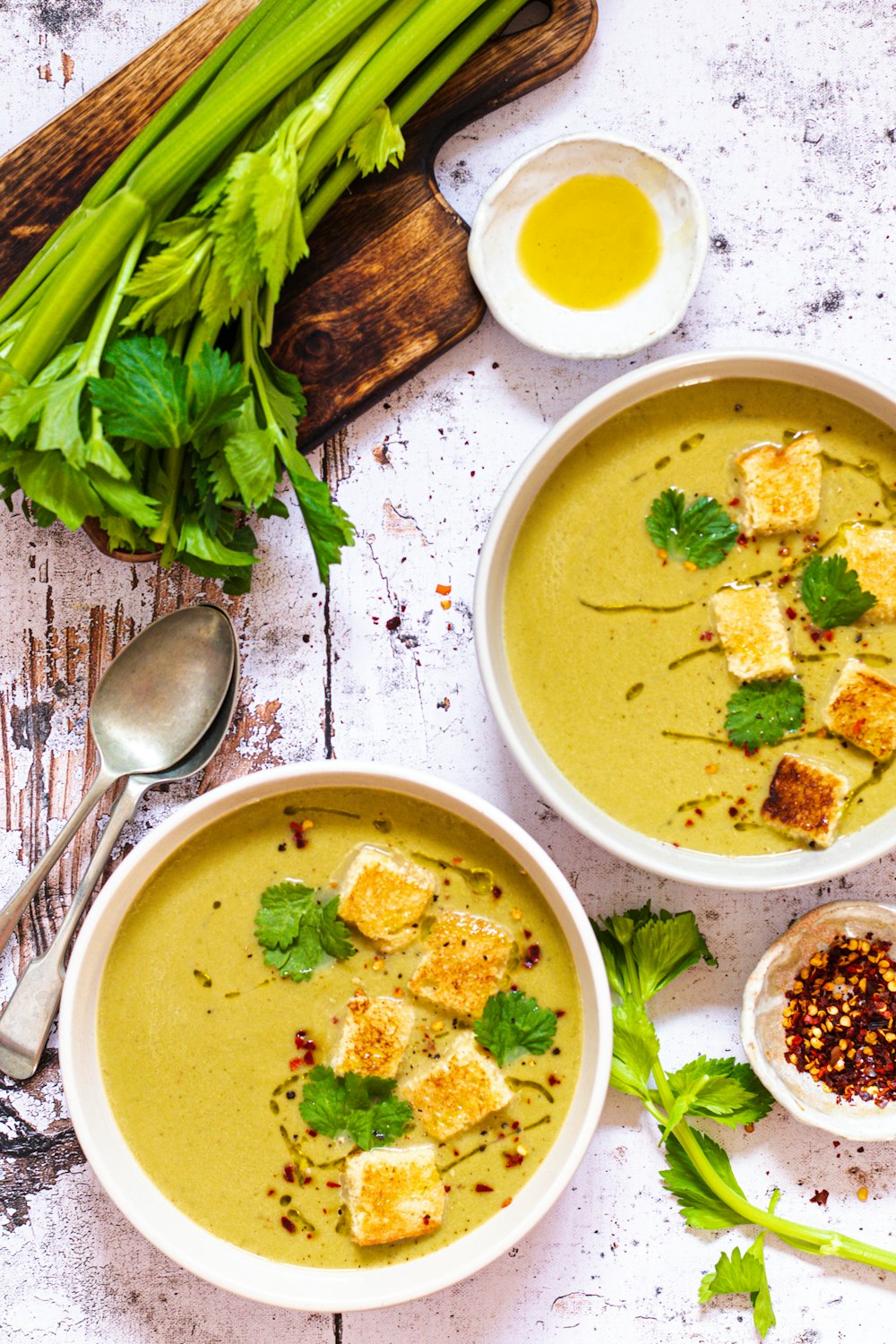 two bowls of soup with tofu and herbs