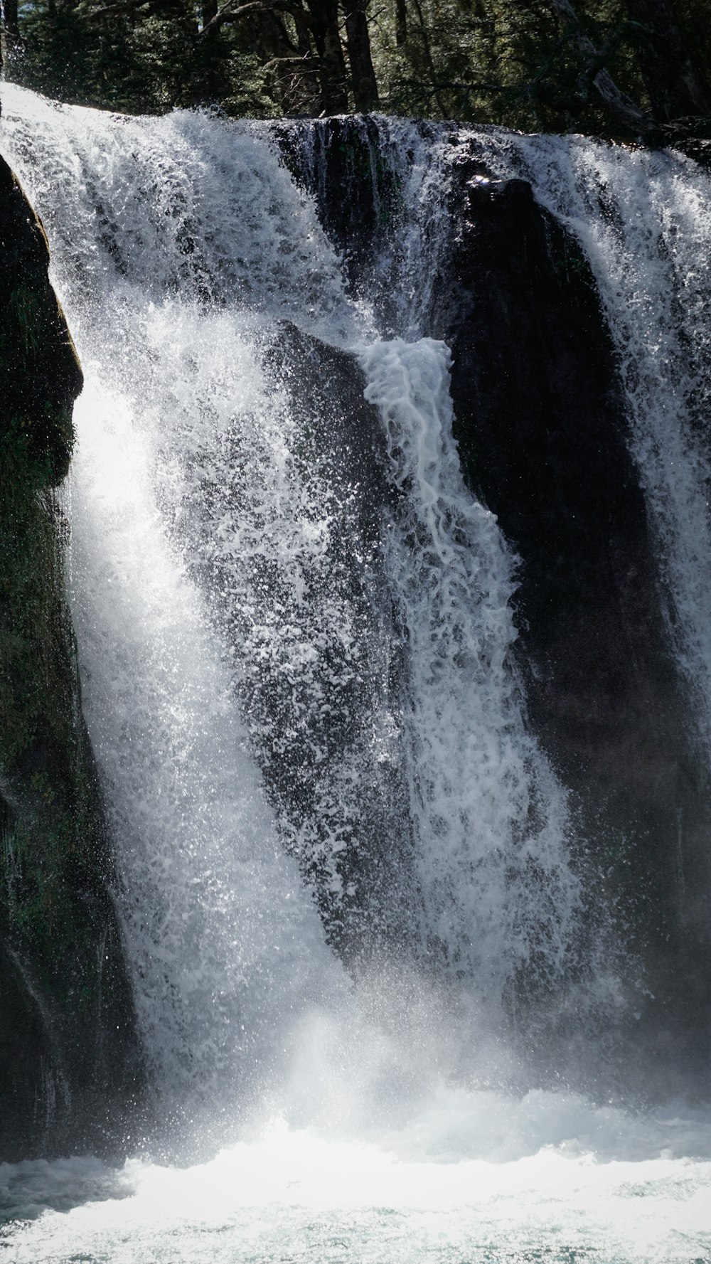 a man riding a surfboard in front of a waterfall