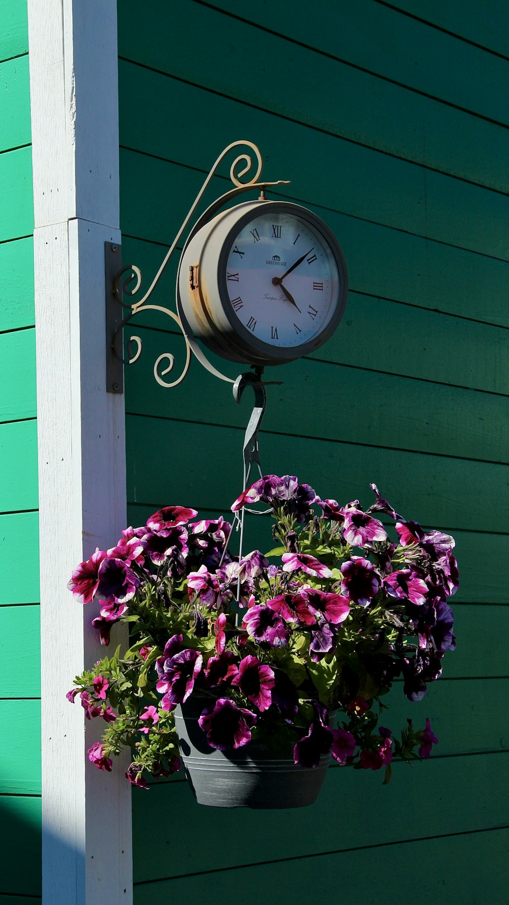 a clock mounted to the side of a green building